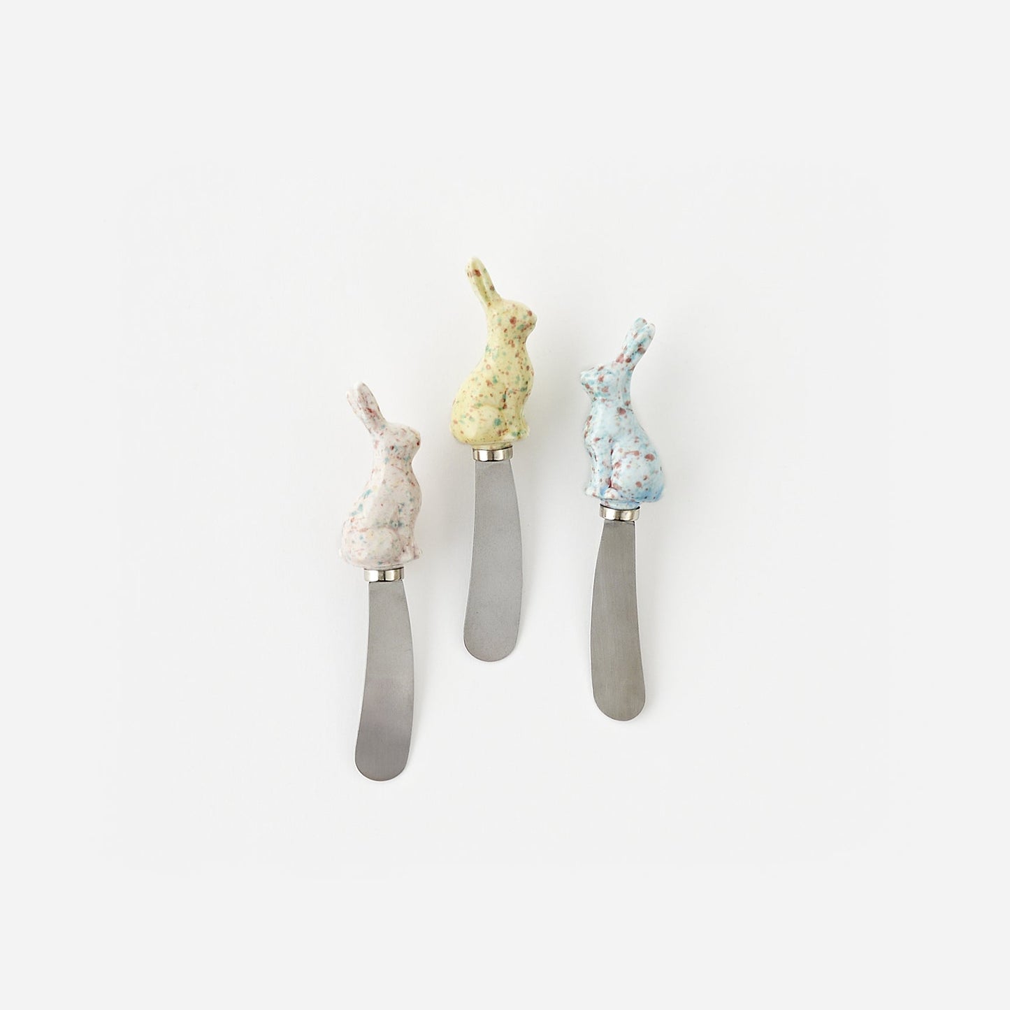 Three decorative butter knives with rabbit handles on a white background