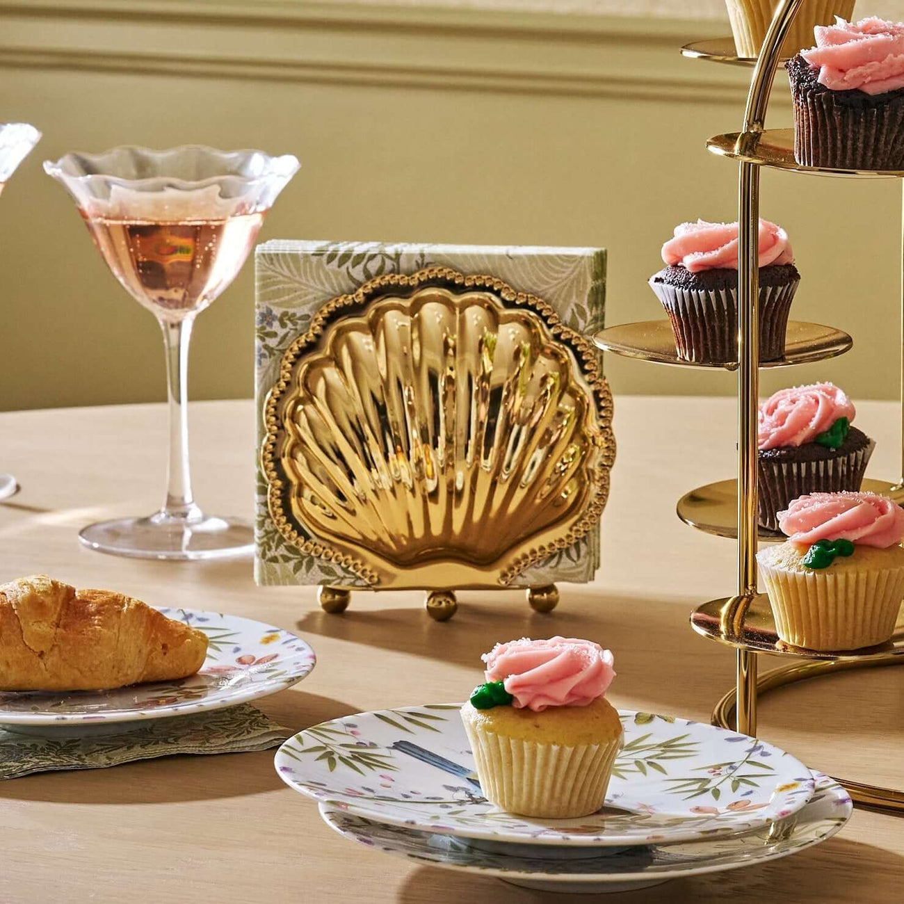 Charming table setup featuring table accessories like gold shell decor, cupcakes, and elegant glassware.