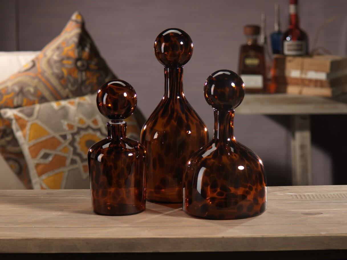 Eclectic collection of three amber glass bottles on a wooden table, complementing an eclectic decor style.