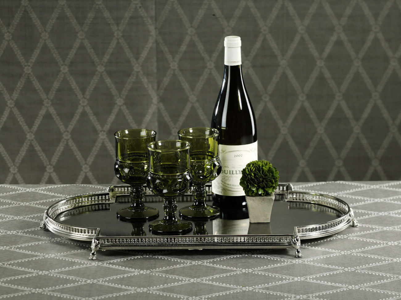 Traditional collection featuring a stylish silver tray with wine and green glasses on a decorative table.