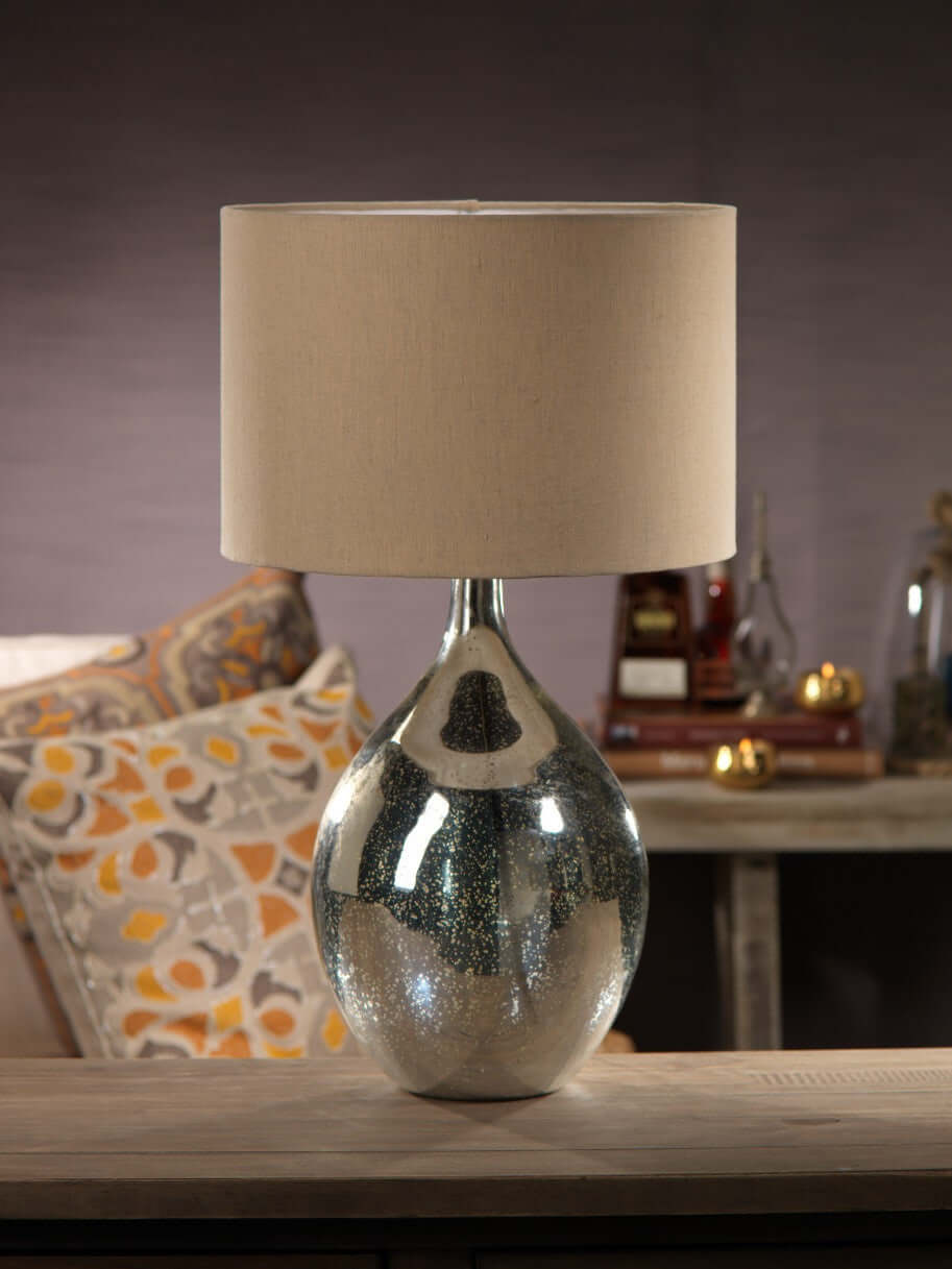 Stylish silver lamp with a beige shade on a wooden table, part of the Lamps collection.
