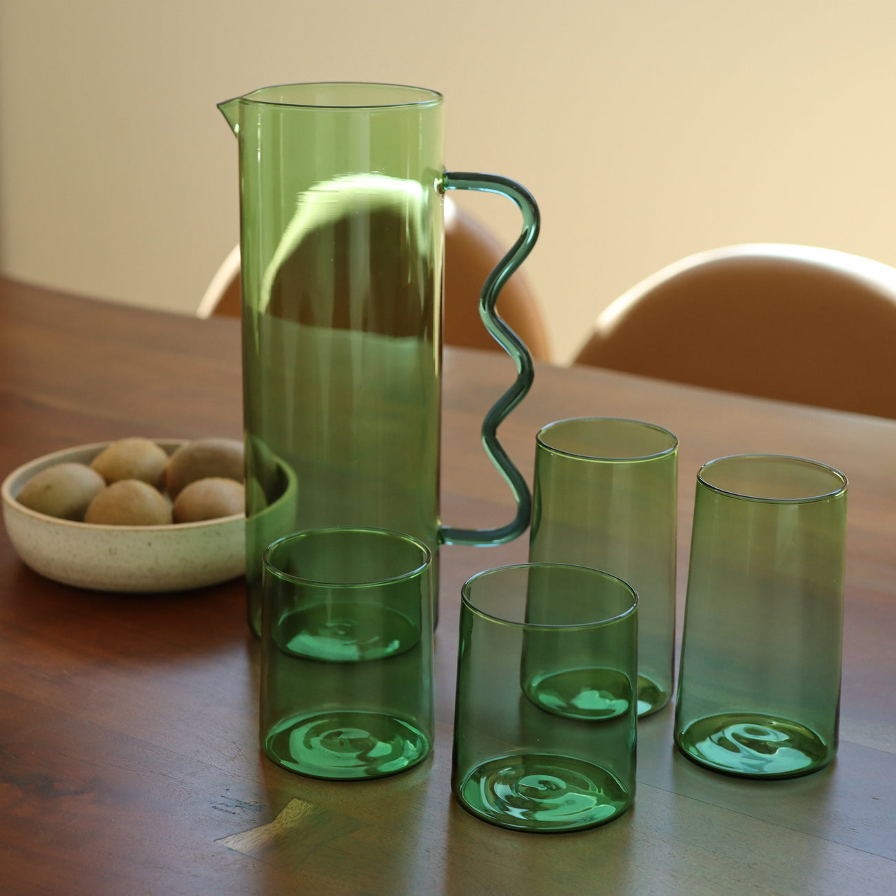 A stylish green pitcher and four matching carafes displayed on a wooden table, perfect for Pitchers & Carafes collection.