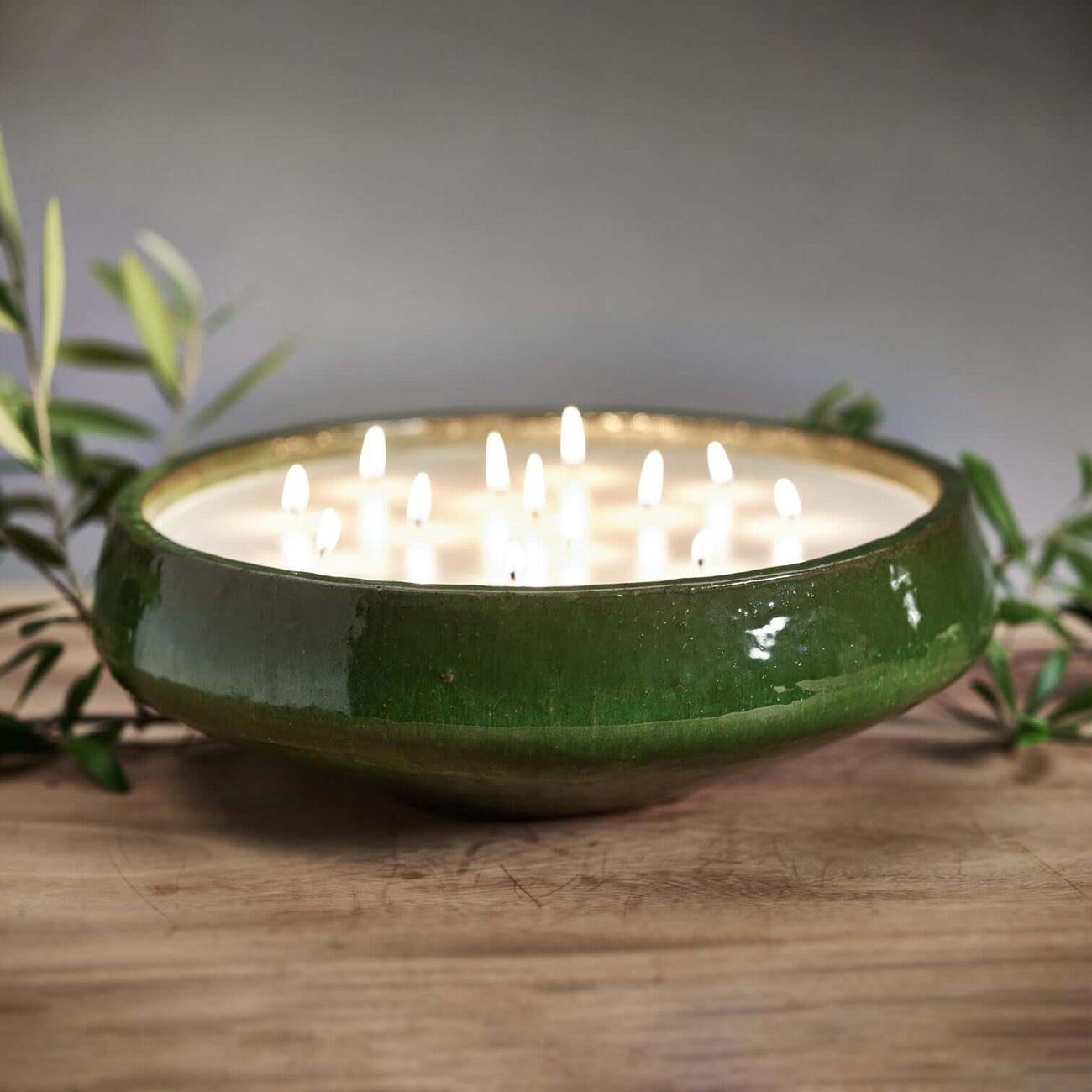 A round green candle bowl with multiple lit candles, perfect for creating a cozy atmosphere with fruity fragrances.