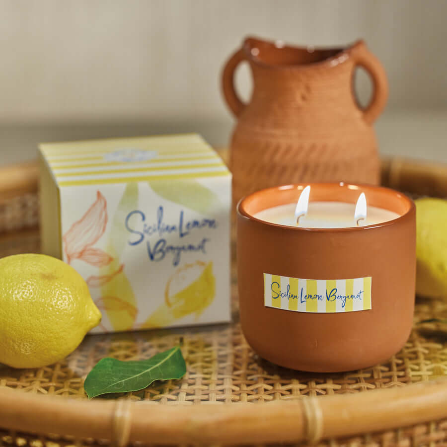 Citrus Fragrances candle with Sicilian lemon and bergamot in a warm setting with fresh lemons.