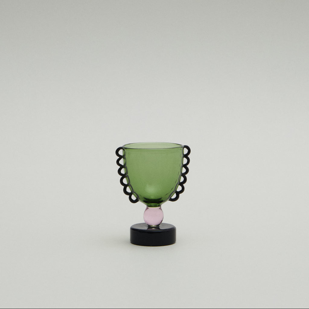 Green glass object with black decorative rim on a white background