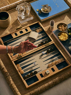 A beautiful Marbella Backgammon Set displayed on a textured table surface, showcasing elegant game pieces and dice.