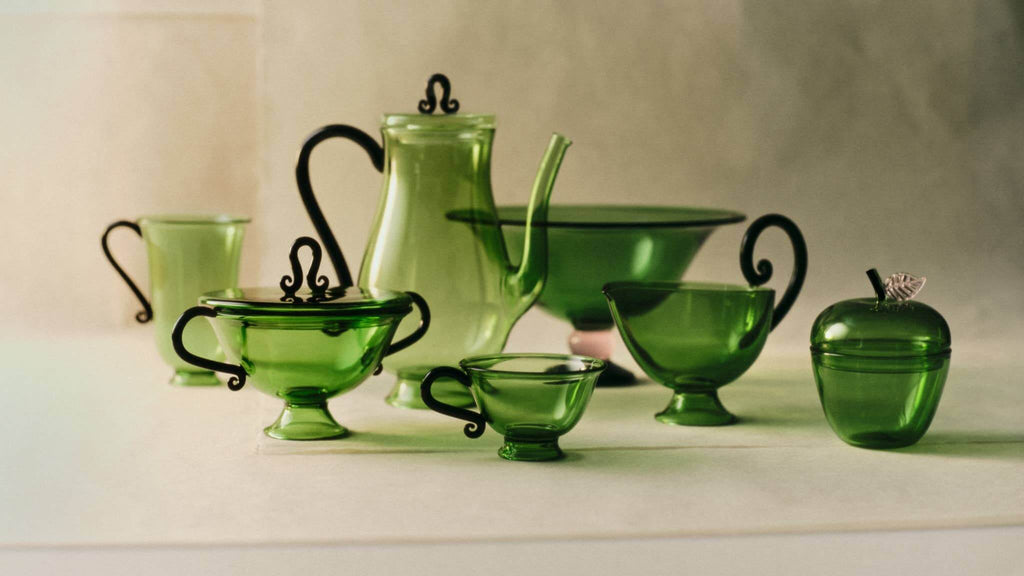 Collection of green glass tea set and La Pomme, Green apple-shaped storage jar on display.