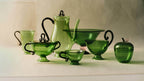Collection of green glass tea set and La Pomme, Green apple-shaped storage jar on display.