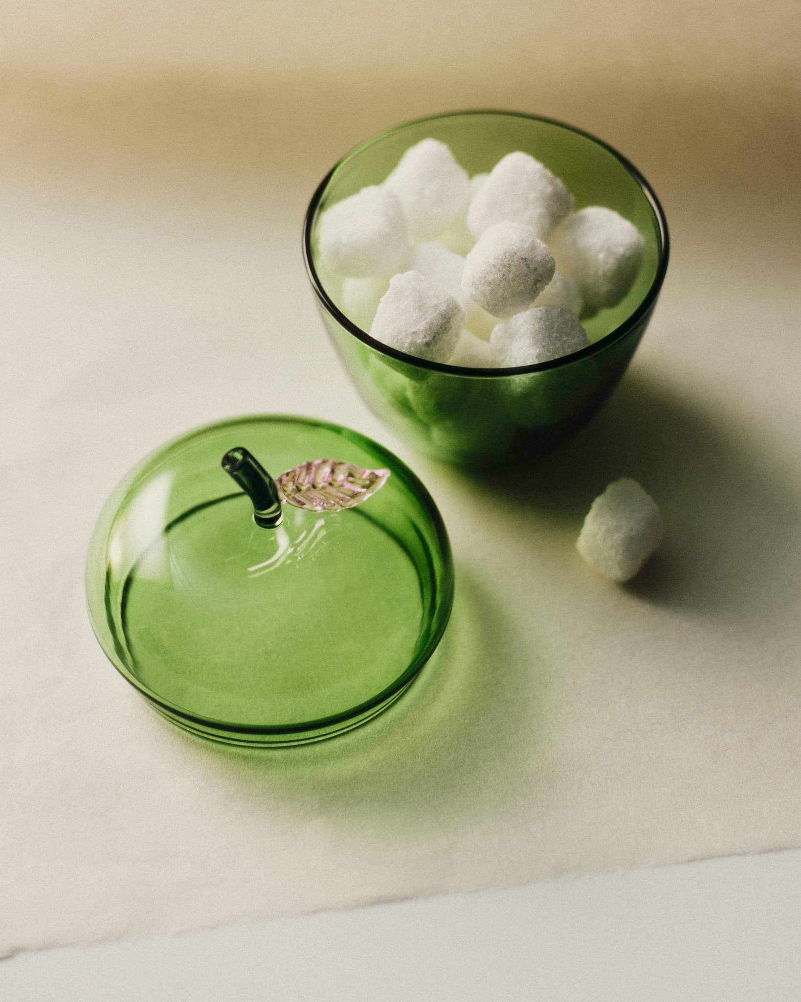 La Pomme, Green decorative jar with sugar cubes and a lid shaped like an apple with a metallic leaf.