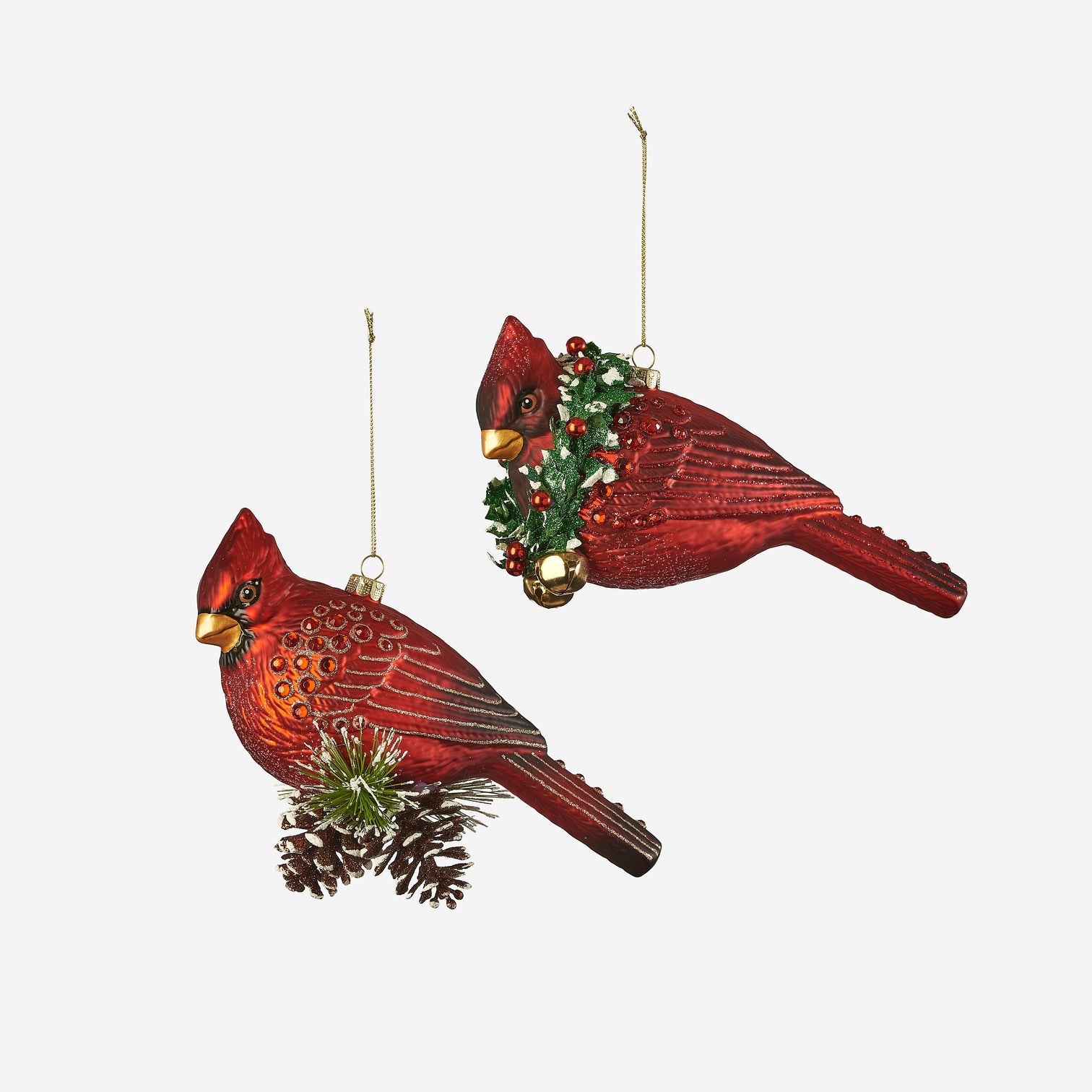 Two red cardinal bird ornaments with pinecones and berries on a white background