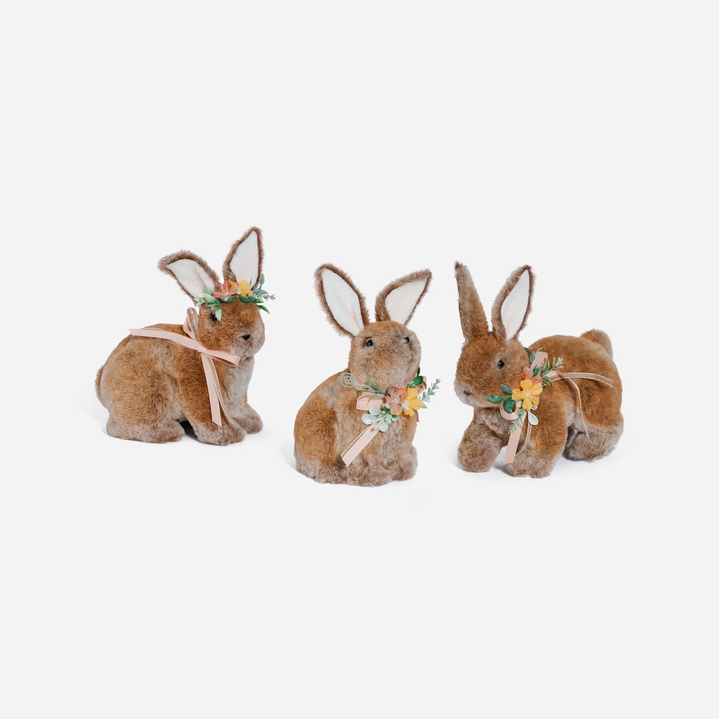 Three plush bunny toys with decorative ribbons and flowers on a white background