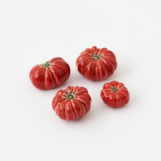 Four red ceramic tomatoes on a white background