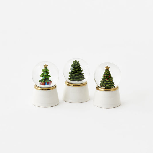 Three small snow globes with Christmas trees on a white background