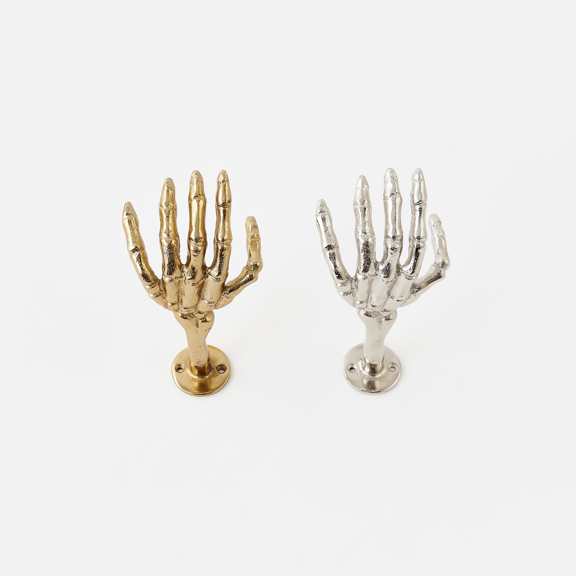 Gold and silver skeleton hand wall hooks on a white background