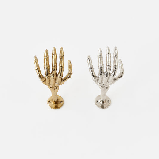 Gold and silver skeleton hand wall hooks on a white background