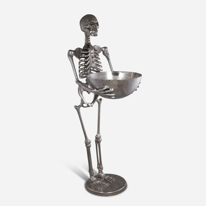Metallic skeleton figurine holding a bowl on a white background