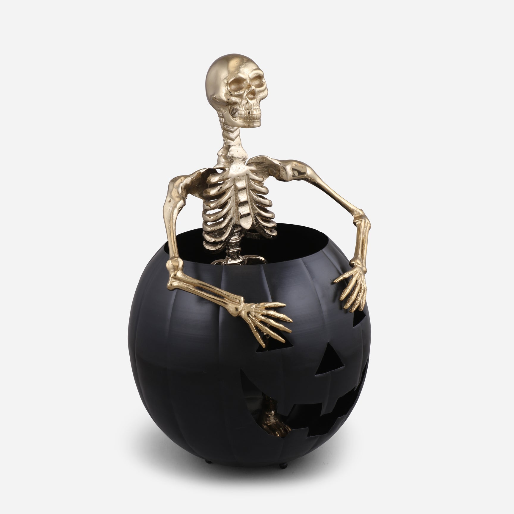 Gold skeleton figure inside a black pumpkin on a white background