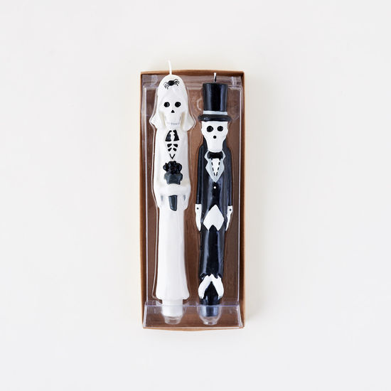 Two skeleton candles, one in a top hat and bow tie, the other in a suit, in packaging on a white background.