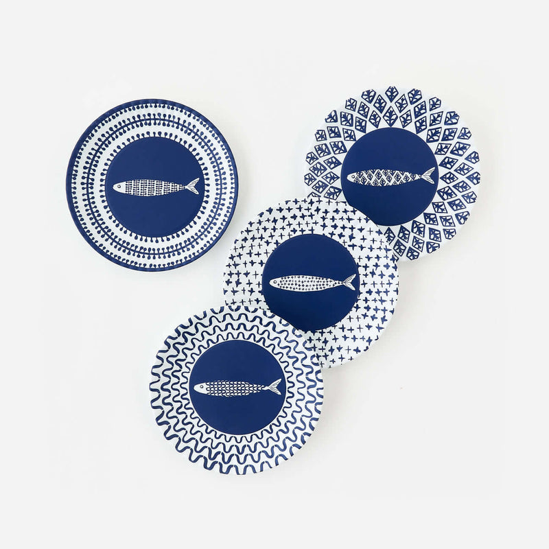 Set of four assorted fish-themed melamine appetizer plates with blue paper plate patterns.