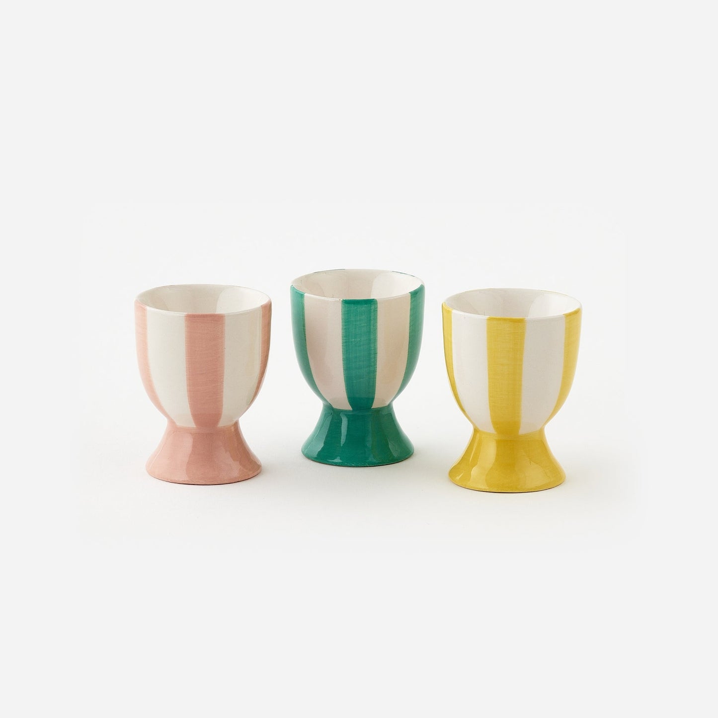 Three colorful egg cups with vertical stripes on a white background