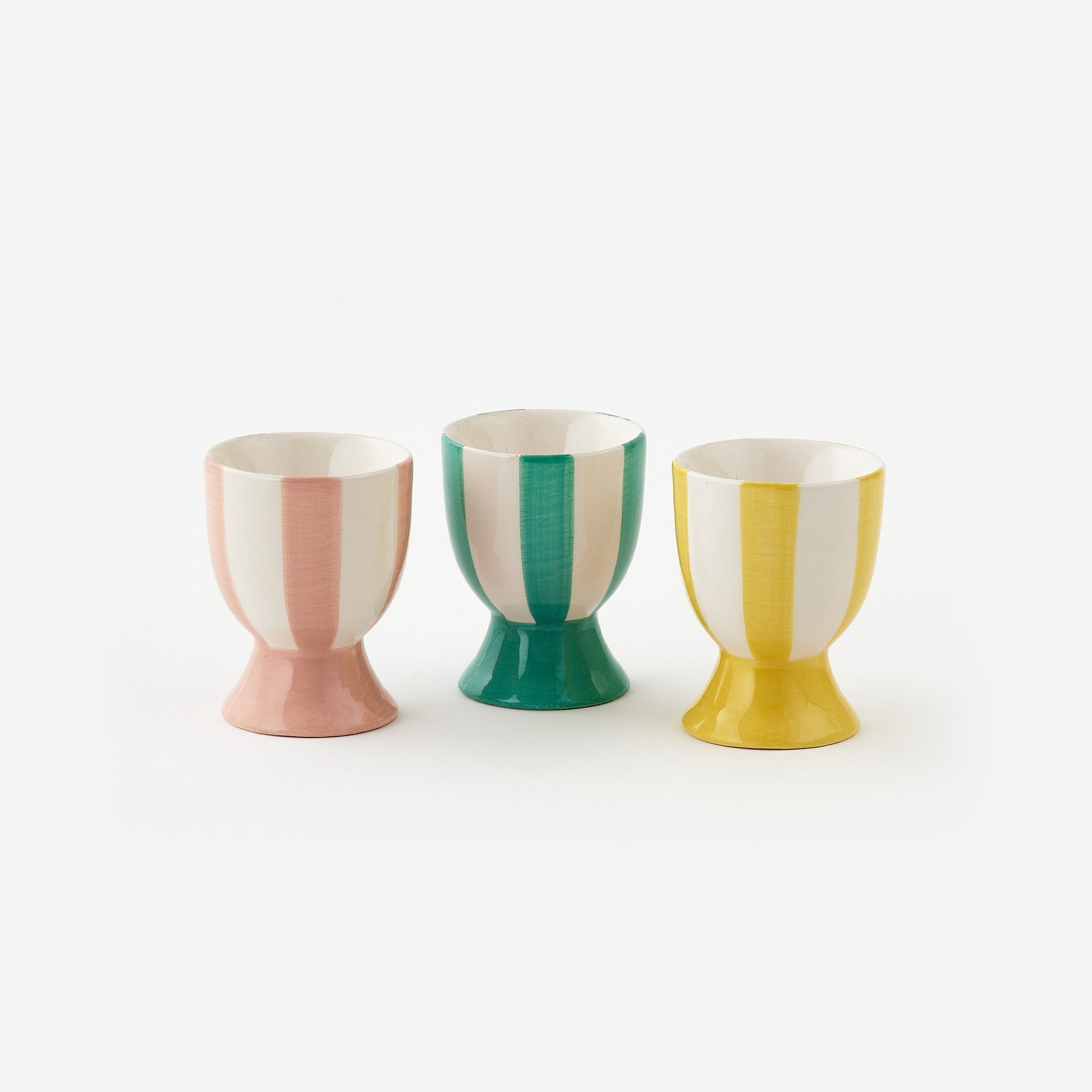 Three colorful egg cups with vertical stripes on a white background