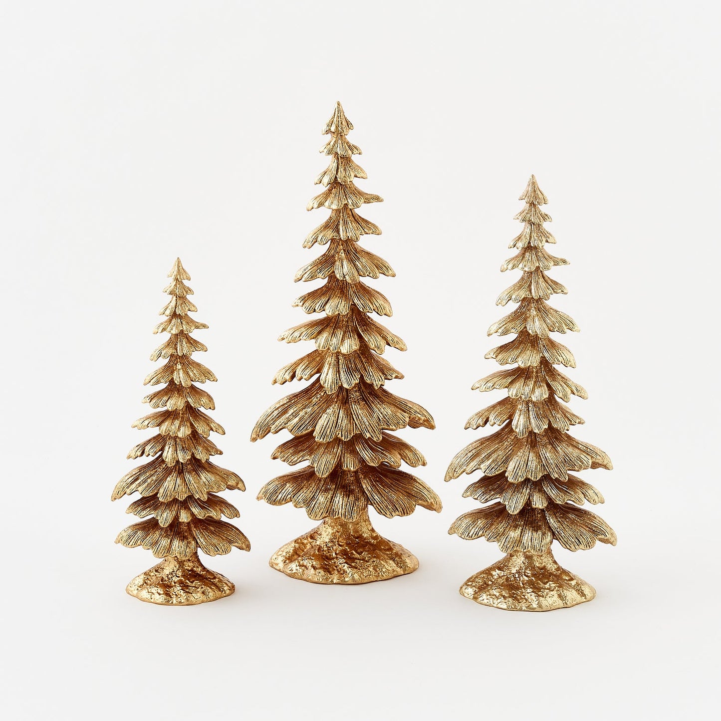 Three gold Christmas tree figurines of varying heights on a white background