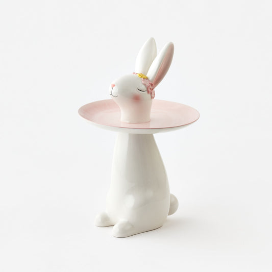 Ceramic rabbit figurine with a pink stand on a white background