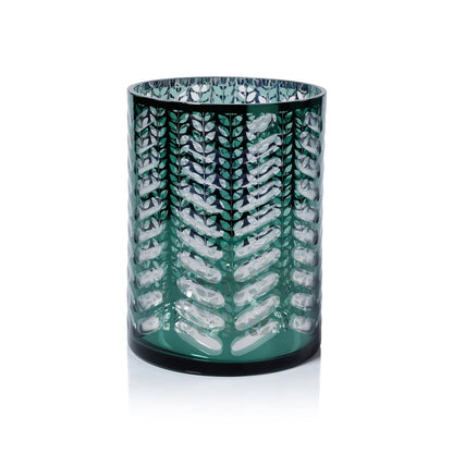 Green glass candle holder with white leaf pattern on a white background