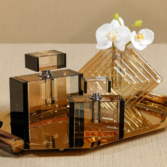 Gold perfume bottles with a decorative stand and white orchids on a beige background
