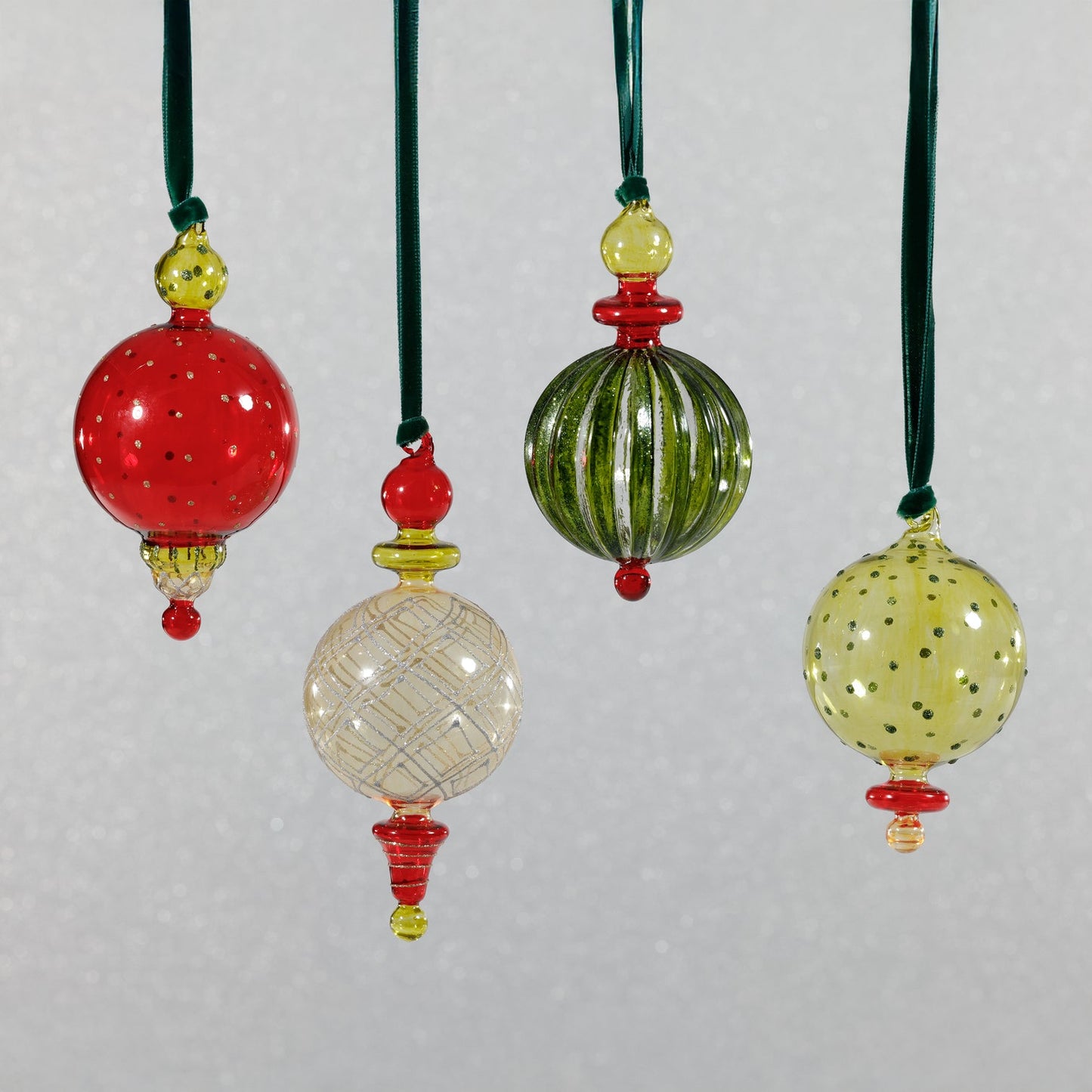 Set of colorful glass ornaments with green, red, and yellow accents on a light gray background.