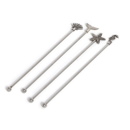 Set of four white swizzle sticks with starfish and shell designs on a white background