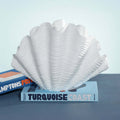 Belize Resin Decorative Shell Vase displayed on books with a white glossy finish and undulating ridges.
