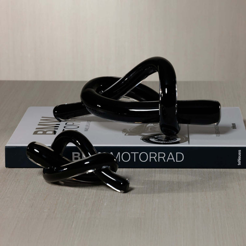 Obsidian Glass Knot Paperweight showcased on a book, featuring modern black glass in a sculptural design.