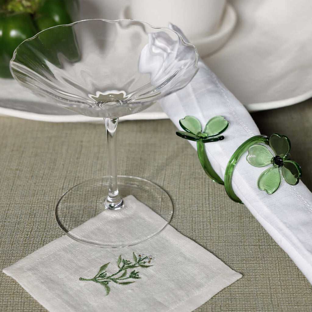 Four Botanica Glass Flower Napkin Rings - Boxed (Set of 4) on a spring table with a glass and embroidered napkin.