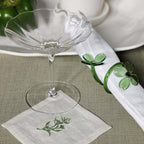 Four Botanica Glass Flower Napkin Rings - Boxed (Set of 4) on a spring table with a glass and embroidered napkin.
