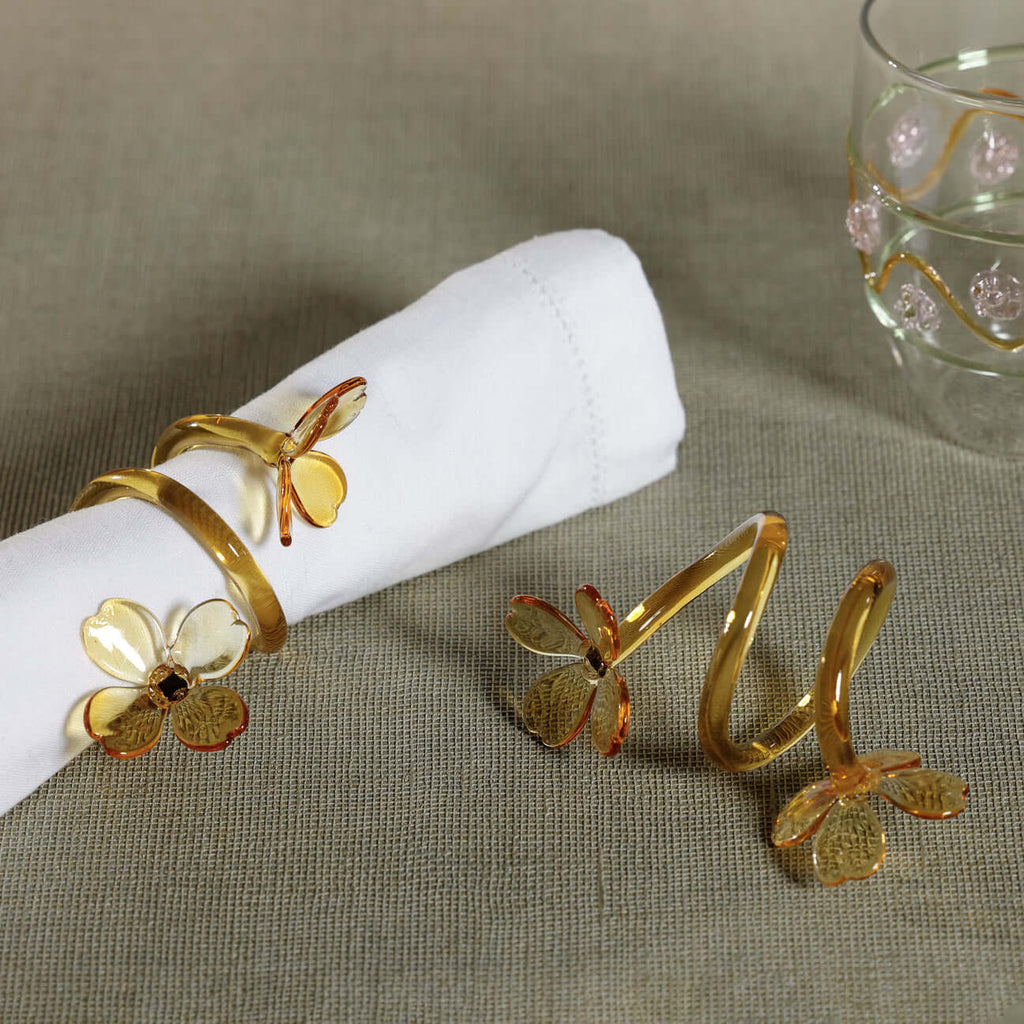 Four Botanica Glass Flower Napkin Rings - Boxed (Set of 4) displayed elegantly with white napkin.