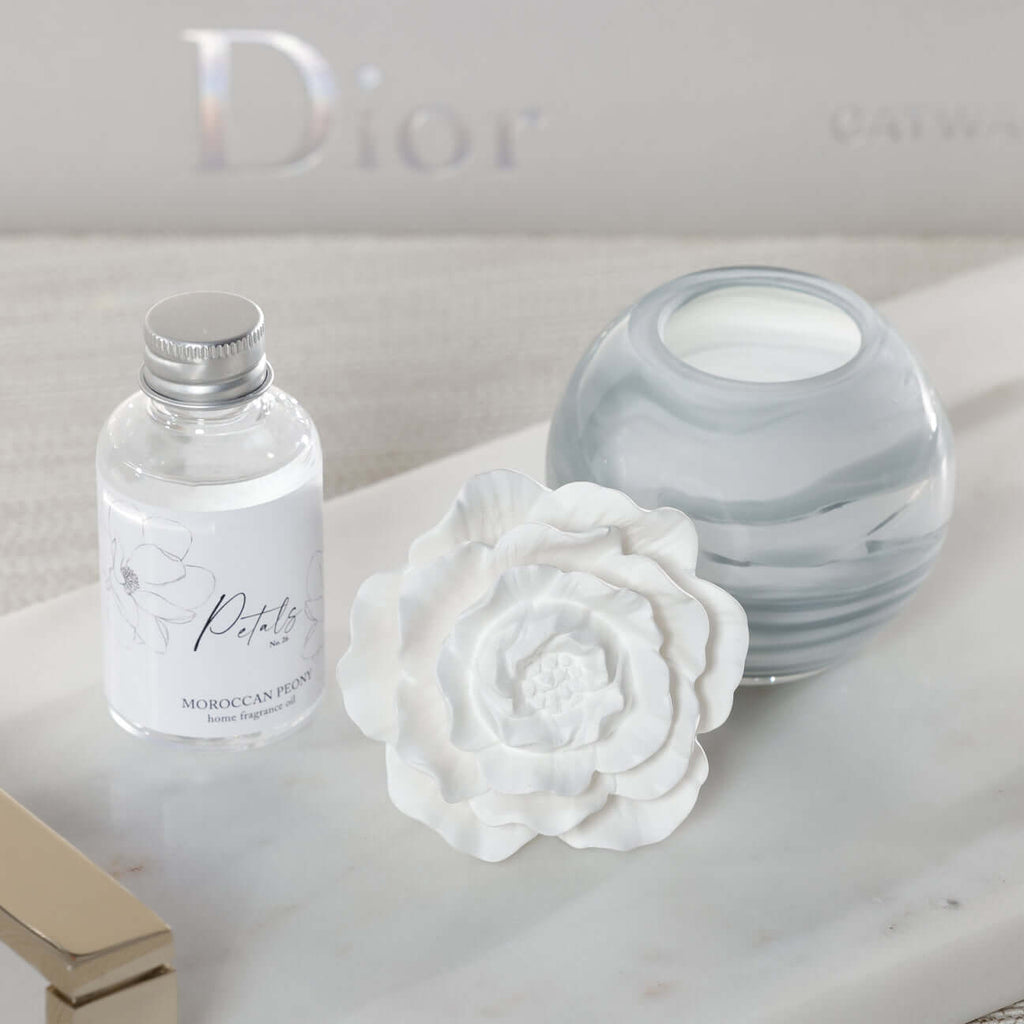 Petals Porcelain Diffuser - Small with marbled glass vessel and delicate porcelain flower on a marble tray.