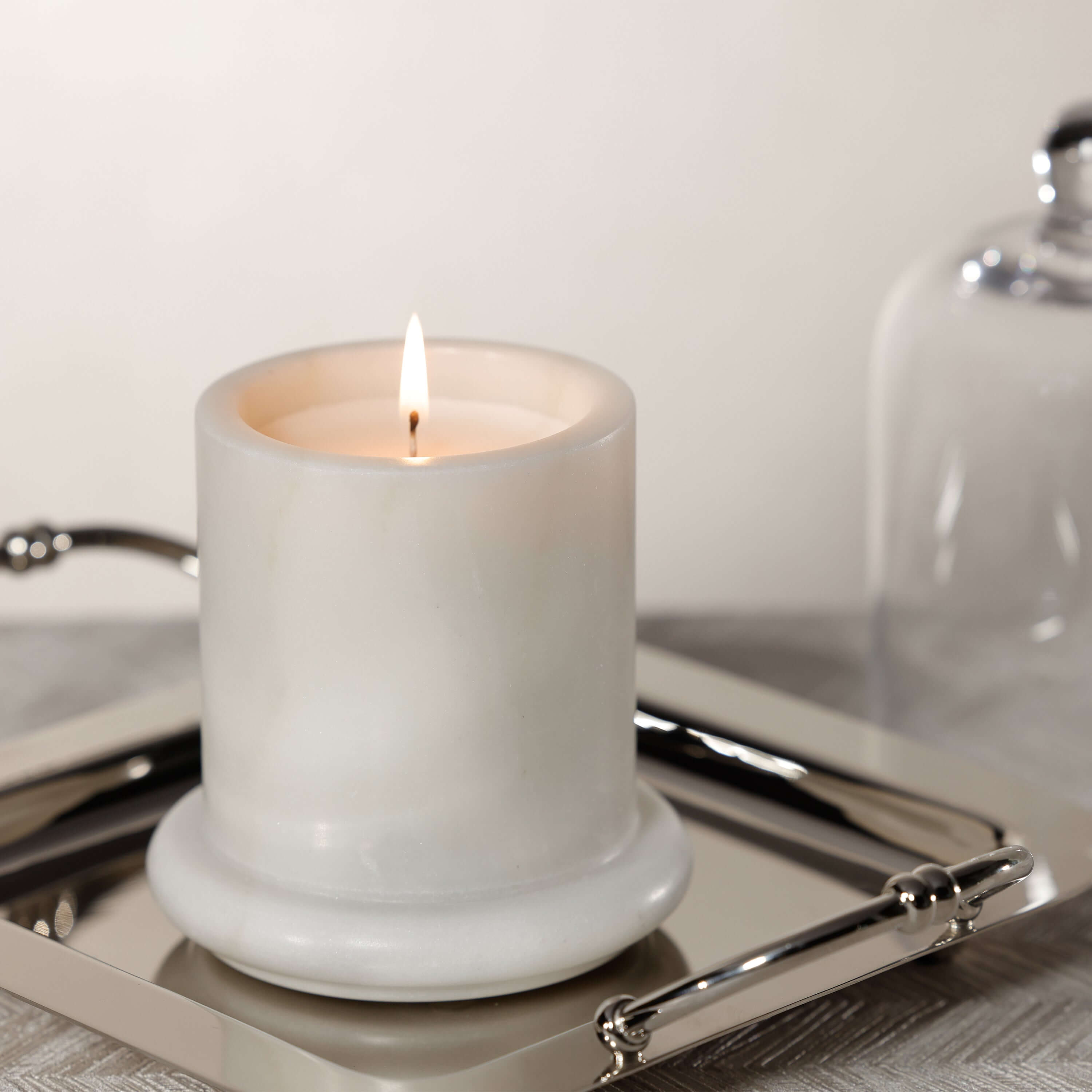 Marbella Scented Candle Jar with Cloche on a silver tray, featuring a flickering flame and elegant design.