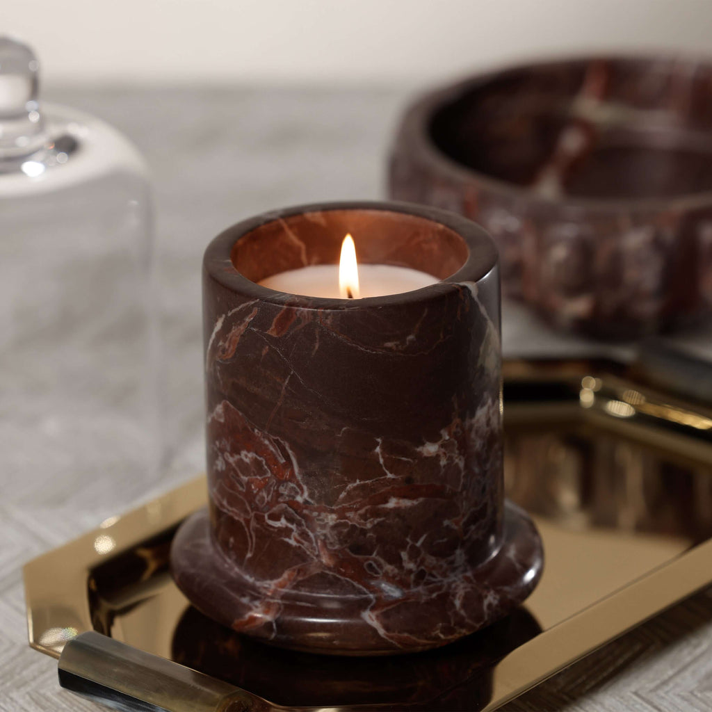 Marbella Scented Candle Jar with Cloche atop a gold tray, showcasing rich marble detail and warm flame.