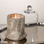 Marbella Scented Candle Jar with Cloche on a mirrored tray, showcasing natural marble and a hand-blown glass cloche.