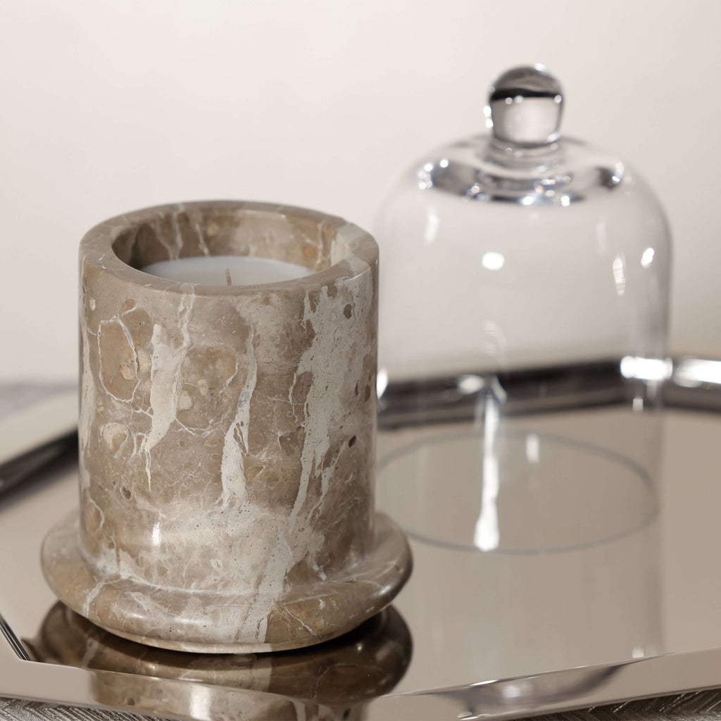 Marbella Scented Candle Jar with Cloche on a reflective tray, showcasing unique marble texture and glass cover.