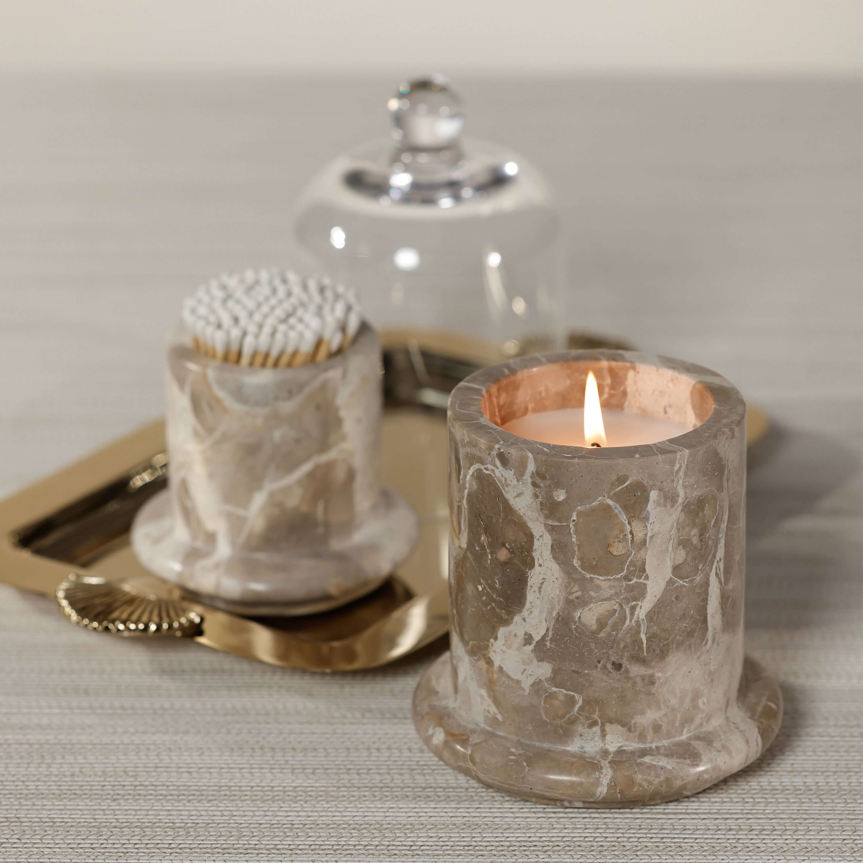 Marbella Scented Candle Jar with Cloche elegantly displayed on a tray, showcasing its unique marble design and warm glow.