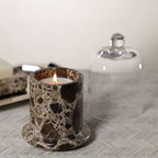Marbella Scented Candle Jar with Cloche featuring a lit candle in a natural marble jar.