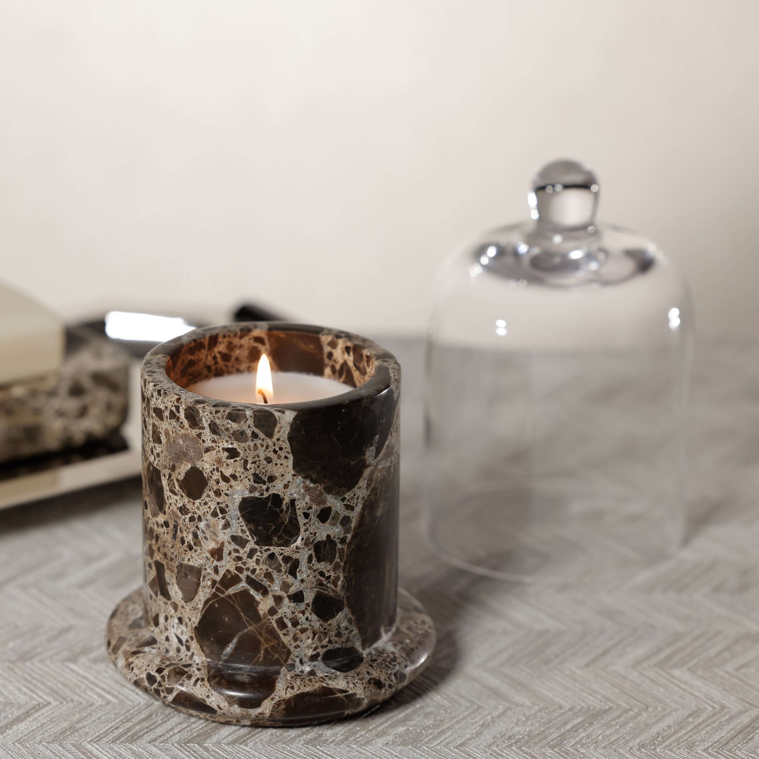 Marbella Scented Candle Jar with Cloche featuring a lit candle in a natural marble jar.