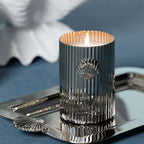 Cap Ferrat Fan Shell Design Candle in Gift Box displayed on a silver tray with a lit wick and fluted metal vessel.