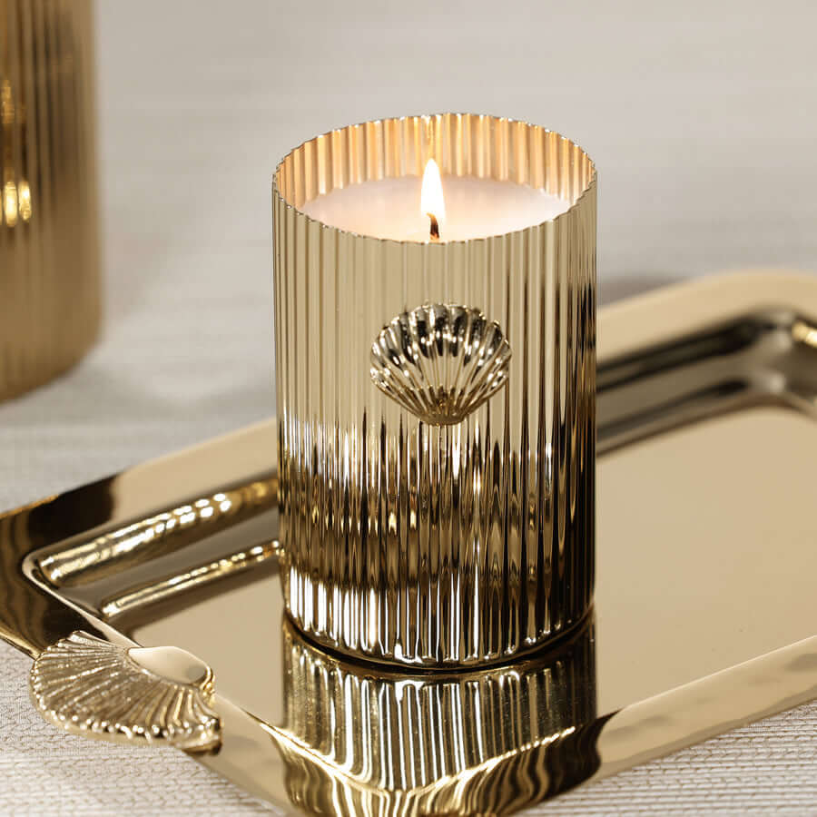 Cap Ferrat Fan Shell Design Candle in Gift Box displayed on a metallic tray, featuring a fluted gold vessel and lit wick.
