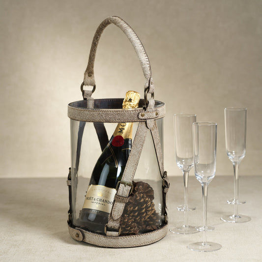 Champagne bottle in a decorative holder with three glasses on a neutral background