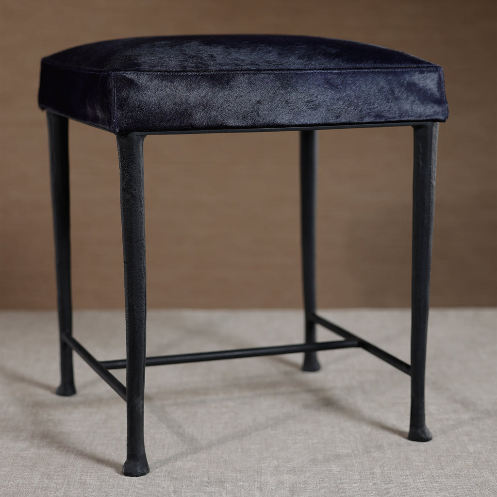 Black stool with a cushioned seat on a neutral background