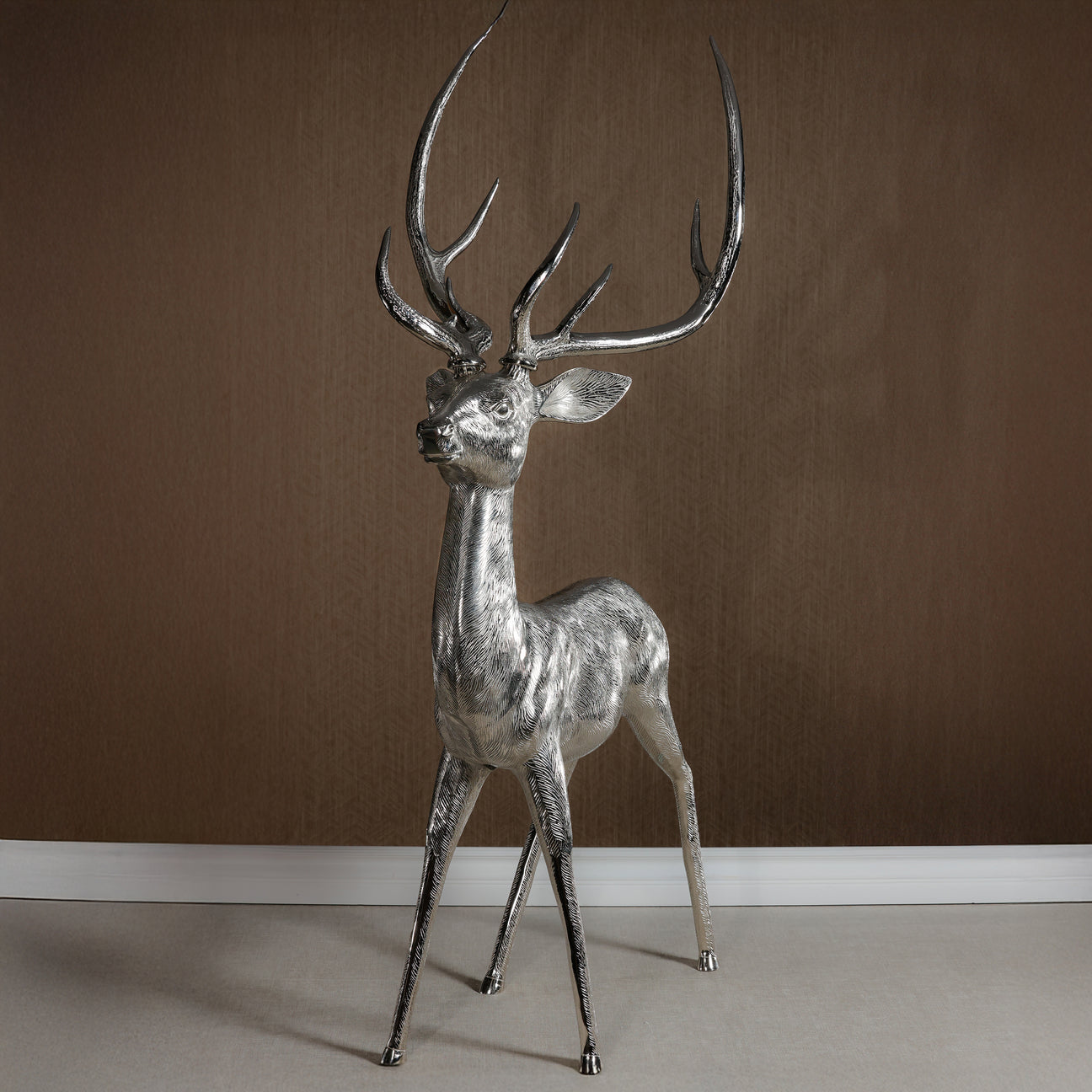 Silver deer statue against a brown wall