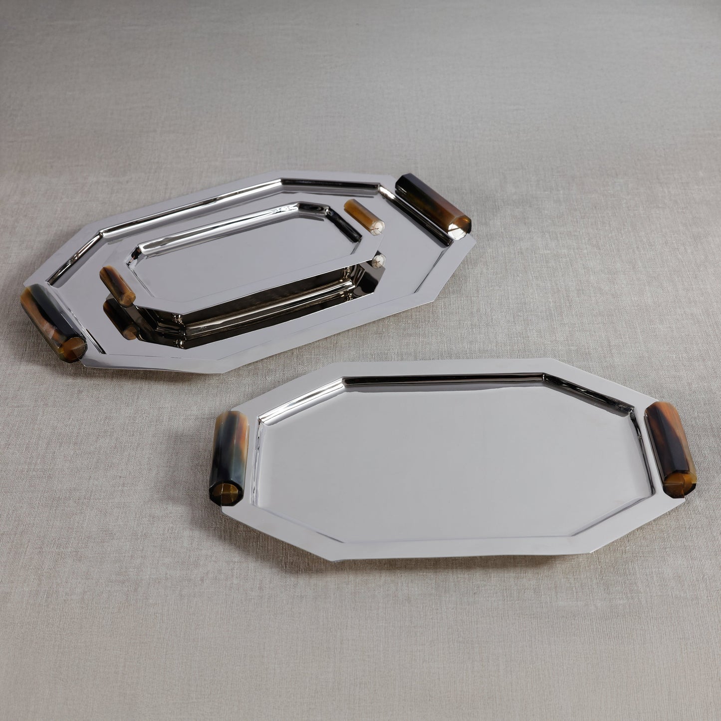 Two metallic trays with wooden accents on a textured surface